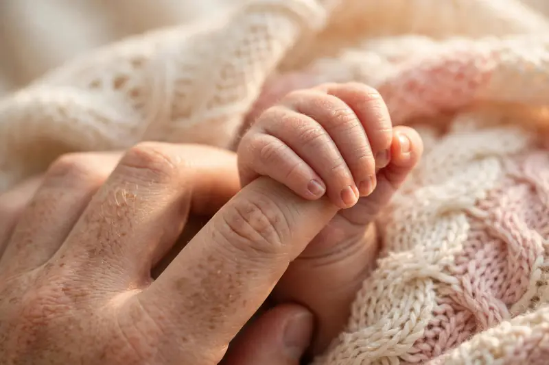 Newborn baby's hand holding a parent's finger